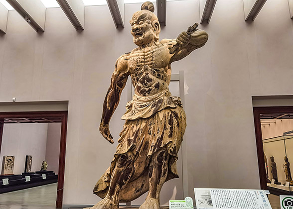 A tall buddhist sculpture with serious facial expression