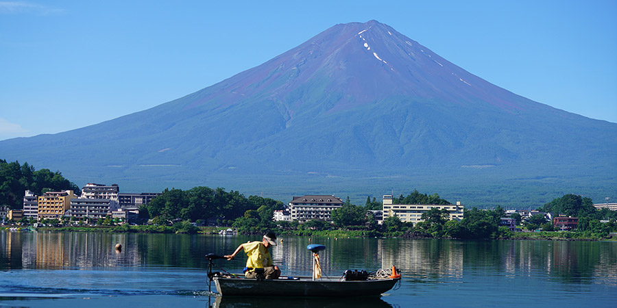 Visitors are sitting in a boat and watching Mt. Fuji faraway