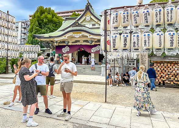 Visitors, decorative lanterns beside, & shrine building behind
